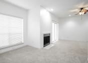 Thumbnail 15 of 33 - an empty living room with a fireplace and a ceiling fan