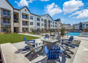 Thumbnail 31 of 37 - an outdoor patio with chairs and a fire pit and an apartment building