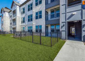 Thumbnail 29 of 37 - an exterior view of an apartment building with green grass and a sidewalk