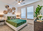 Thumbnail 6 of 50 - A bedroom with a bed, a fan, and a plant.