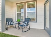 Thumbnail 11 of 50 - A small table with a plant on it sits between two chairs on a porch.