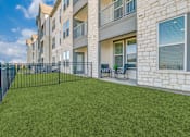 Thumbnail 50 of 50 - A grassy area in front of a building with a black fence.
