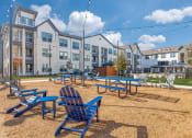 Thumbnail 20 of 37 - a playground with blue chairs and picnic tables in front of an apartment building