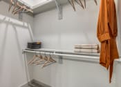 Thumbnail 11 of 37 - a walk in closet with a white wall and a rack with hangers and towels