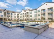 Thumbnail 26 of 37 - our apartments feature a community pool and spa with an apartment building in the background