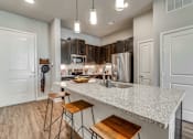 Thumbnail 12 of 29 - A kitchen with a white countertop and wooden stools.