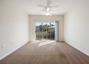 Thumbnail 6 of 30 - A room with a ceiling fan and a sliding glass door leading to a balcony.