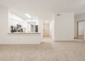 Thumbnail 2 of 41 - an empty living room with a kitchen and a door to a hallway