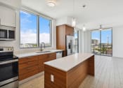 Thumbnail 36 of 66 - a kitchen with wooden cabinetry and a large center island with a white countertop