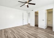 Thumbnail 7 of 21 - A room with a ceiling fan and wooden flooring.
