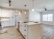 Thumbnail 5 of 65 - an open kitchen and living room with white cabinets and a large counter top