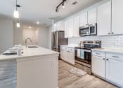 Thumbnail 2 of 65 - a kitchen with white cabinets and a counter top and a stove