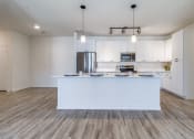 Thumbnail 7 of 65 - an open kitchen and living room with white cabinets and a large island