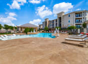 Thumbnail 50 of 65 - a resort style pool with lounge chairs and a building in the background