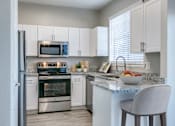Thumbnail 1 of 22 - A kitchen with a bowl of fruit on the counter.