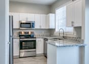 Thumbnail 2 of 22 - A kitchen with a granite countertop and stainless steel appliances.