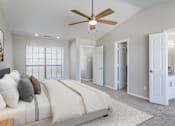 Thumbnail 12 of 22 - A bedroom with a large bed and a ceiling fan.