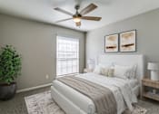 Thumbnail 8 of 22 - A bedroom with a bed, a ceiling fan, and a potted plant.