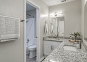 Thumbnail 7 of 22 - A bathroom with a granite counter top and white fixtures.