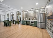 Thumbnail 19 of 21 - A kitchen with green chairs and a patterned wallpaper.