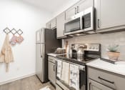 Thumbnail 3 of 20 - an apartment kitchen with stainless steel appliances and white cabinets