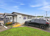 Thumbnail 21 of 23 - A black SUV is parked in front of a building with a blue sign that reads "CARS 4 LIFE."