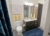 Thumbnail 13 of 36 - a bathroom with a toilet and a sink and a mirror