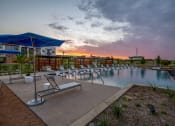 Thumbnail 33 of 36 - a swimming pool with chairs and umbrellas at sunset