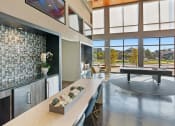Thumbnail 21 of 36 - a living room with a ping pong table and a kitchen with a large window
