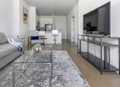 Thumbnail 1 of 11 - A modern living room with a grey sofa and a glass coffee table.