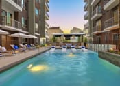 Thumbnail 10 of 17 - a swimming pool with lounge chairs and umbrellas in front of an apartment building