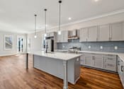 Thumbnail 32 of 38 - A modern kitchen with a large island and wooden floors.