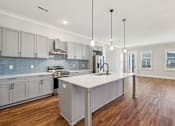 Thumbnail 16 of 38 - A modern kitchen with a large island and wooden floors.