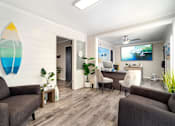 Thumbnail 1 of 22 - a living room with a couch and a desk and a surfboard