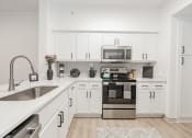 Thumbnail 8 of 41 - a spacious kitchen with white cabinets and stainless steel appliances