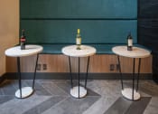 Thumbnail 21 of 30 - a trio of tables in front of a teal wall with two bottles of wine on top