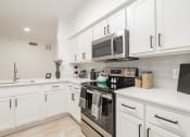 Thumbnail 3 of 41 - a kitchen with white cabinets and a stove and a microwave