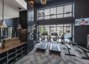 Thumbnail 22 of 30 - a gym with cardio equipment and a large window