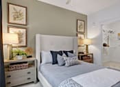 Thumbnail 12 of 47 - A bedroom with a large bed and a nightstand with a lamp.