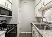 Thumbnail 3 of 24 - A kitchen with a stove, microwave, and sink.