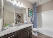 Thumbnail 8 of 22 - a bathroom with granite countertops and brown cabinets