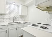 Thumbnail 10 of 21 - A white kitchen with a stove top oven.