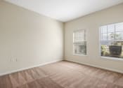 Thumbnail 9 of 30 - A room with a carpeted floor and two windows.