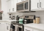 Thumbnail 11 of 41 - a kitchen with white cabinets and a stove and a microwave