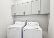 Thumbnail 38 of 38 - Two white washing machines in a laundry room.
