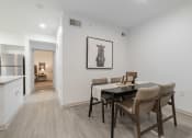 Thumbnail 13 of 35 - a dining room with a table and chairs and a kitchen with a refrigerator