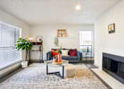 Thumbnail 5 of 40 - A living room with a grey couch, a glass coffee table, and a fireplace.