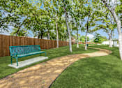 Thumbnail 30 of 34 - A park with a bench and a path.