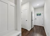 Thumbnail 40 of 56 - A white hallway with a bench and a door.