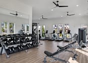 Thumbnail 28 of 47 - A gym with a variety of equipment including treadmills, weights, and exercise machines.